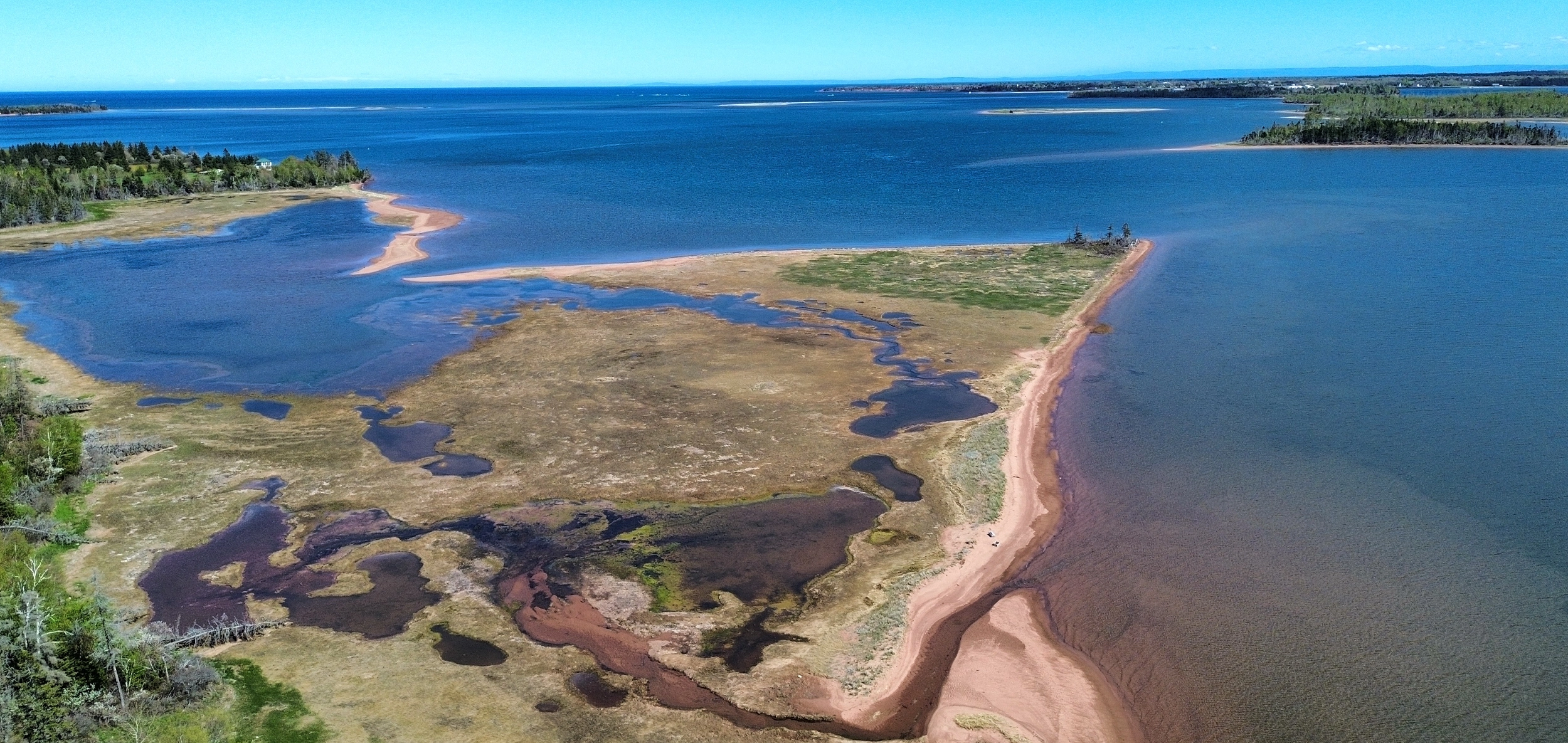 Aerial view of red sandbars and tidal flats meeting the blue bay near the cabin